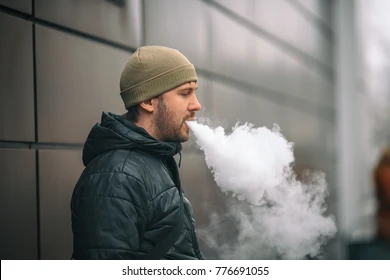 User vaping Ace of Spades pen in city street